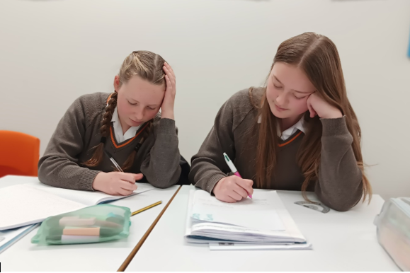 A couple of girls sitting at a table

Description automatically generated